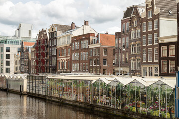 Amsterdam floating flower market and tall narrow historic canal houses along the Singel in the center of the capital.