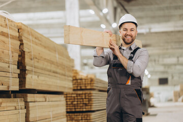 Carpenter carrying wooden plank in lumber warehouse