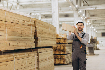 Carpenter carrying wooden plank in timber warehouse for modular building