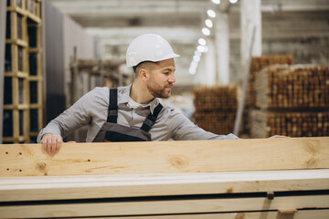 Carpenter checking wooden planks in warehouse for modular building industry