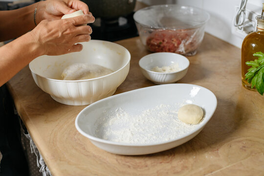female hands preparing dough balls by filo for byrek