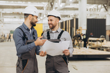 Engineers discussing blueprint in modular building factory