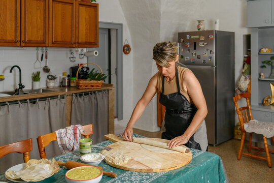 Woman rolls out dough with a rolling pin