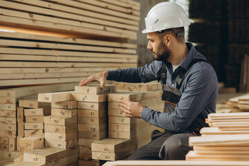 Carpenter inspecting wooden planks in timber warehouse for modular building