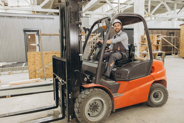 Construction worker driving forklift in modular building factory