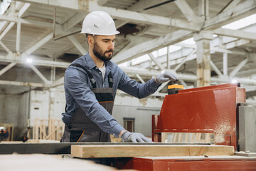 Carpenter operating woodworking machine in modular building factory