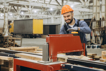 Carpenter operating woodworking machine in timber factory for modular building