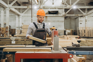 Carpenter working with wood on machine in factory