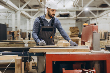 Carpenter measuring wooden plank in timber factory for modular building