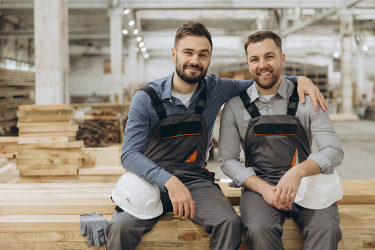 Two carpenters smiling and resting in timber warehouse