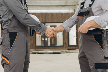 Construction workers shaking hands at modular building site