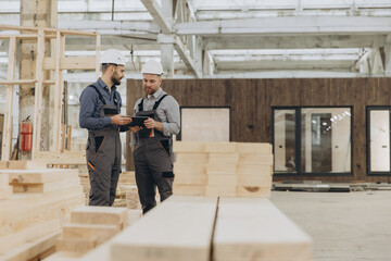 Construction workers using digital tablet in modular building factory