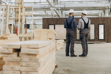 Construction workers discussing building project in modular house factory
