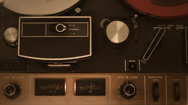 Vintage reel-to-reel tape recorder playing music in a recording studio. Close-up of a vintage reel-to-reel tape recorder playing music, showcasing analog audio technology
