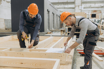 Construction workers building wooden frame in factory for modular building industry