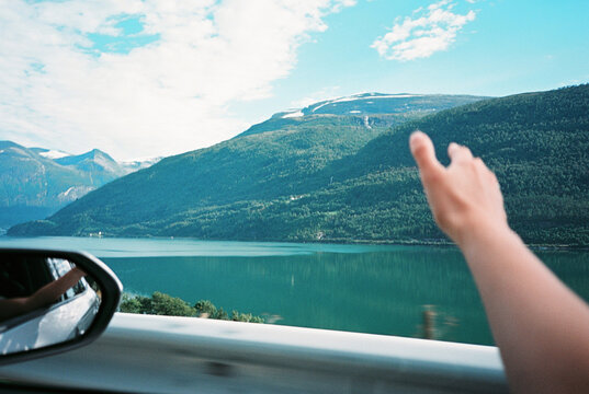 A hand and a view on fjords from the car