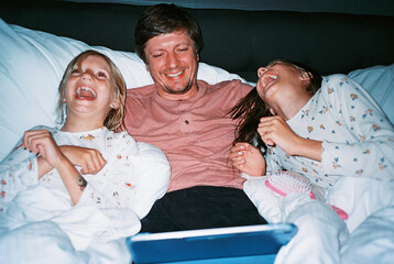 Father with daughters watching video and laughing