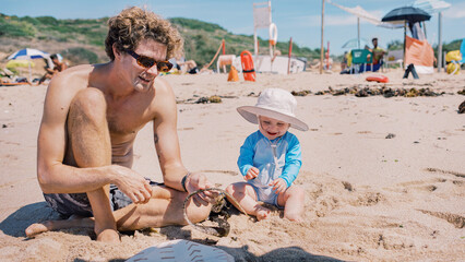 Father and baby playing with seaweed on the beach