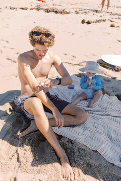 Father and baby playing with seaweed on the beach