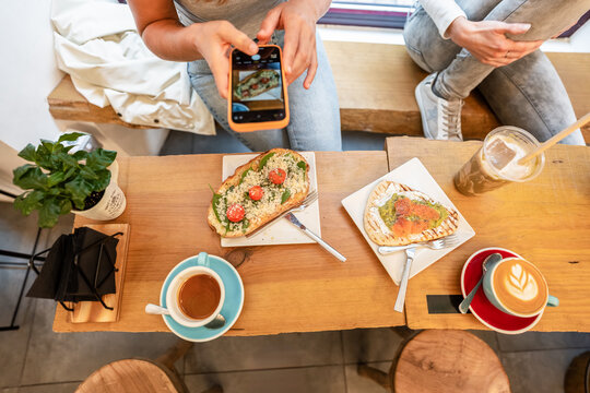 Woman taking pictures of food in cafe with smartphone