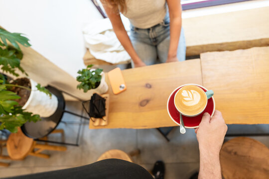 Barista holding latte art coffee in cafe for customer