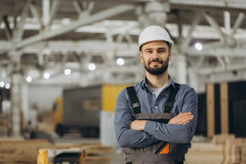 Construction worker posing with crossed arms in modular building factory