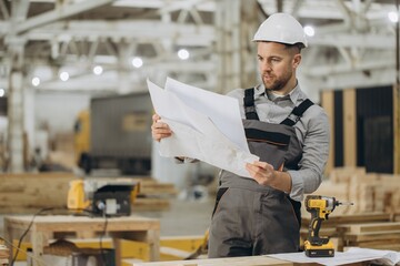 Construction worker reading blueprints in modular building factory