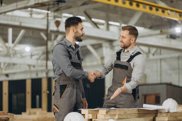 Construction workers shaking hands at modular building factory