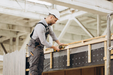 Fototapeta premium Construction worker building modular house using electric screwdriver