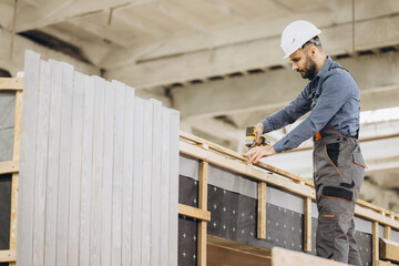 Construction worker building prefabricated modular house in factory