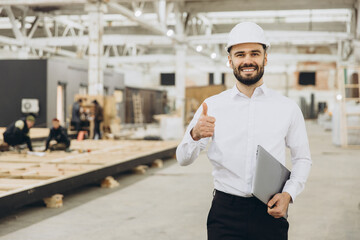 Smiling engineer gesturing thumbs up in modular building factory
