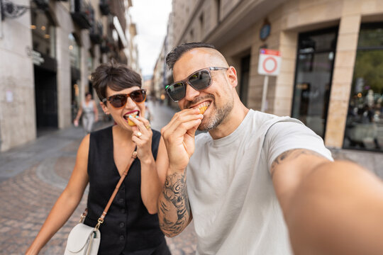Happy couple taking a selfie while eating street food