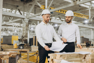 Engineers discussing plans for modular building in factory