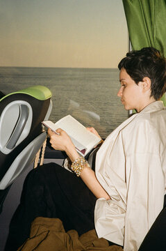 A young woman reads a book while traveling by bus 