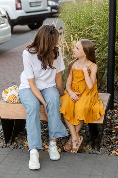 Mother speaks with daughter on bench