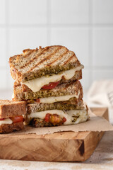 Grilled sandwich panini with mozzarella cheese, cherry tomatoes and pesto close up. Delicious breakfast or snack, traditional italian food