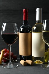 Two bottles of red and white wine with grapes and glasses on wooden background