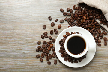 Cup of coffee and coffee beans on wooden background