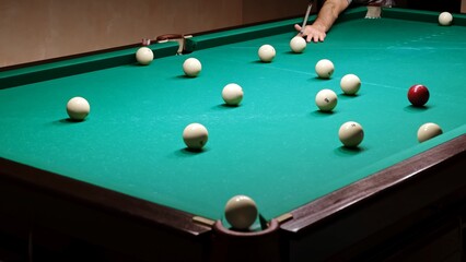Playing Russian billiards on a green table. Billiard player hits the white ball. Good goal. Successful attempt. A great game. Hobby pastime. Corner pocket side view close-up. Professional shot