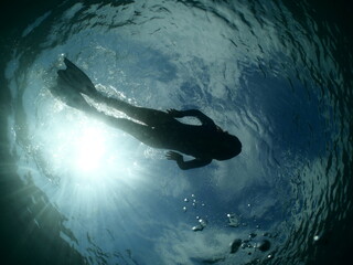 silhouette free diver snorkeling on the surface sky clouds underwater 