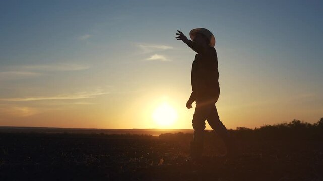 Agriculture. Silhouette of a farmer walking in the field. Landscape fresh harvest concept. Farmer walks through the soils. Silhouette of farmer walking through the field in soild lifestyle soil.