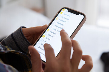 Woman checking packing checklist on smartphone app for vacation