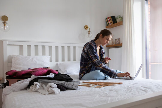 Woman shopping online with credit card and laptop on bed
