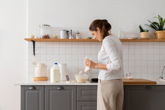 Woman adding ingredients while baking in modern kitchen