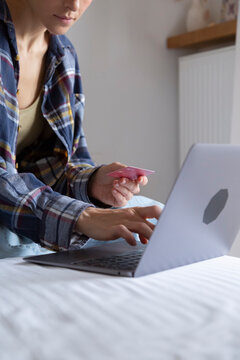 Young woman using credit card and laptop for online shopping at home