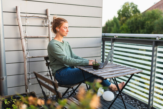 Young Woman Working on Laptop While Enjoying a Smoothie