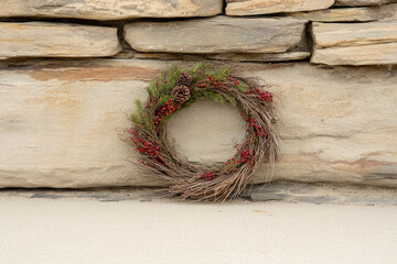 Naklejka premium A wreath with red berries sits on a stone wall