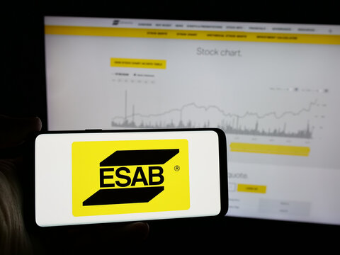 Stuttgart, Germany - 11-07-2024: Person holding smartphone with logo of industrial company ESAB Corporation on screen in front of website. Focus on phone display.