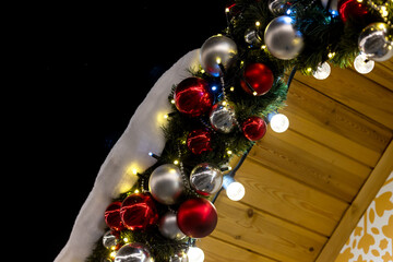 Garland of fir branches with decorations and lighting with a tilt to the left on a dark background. Postcard