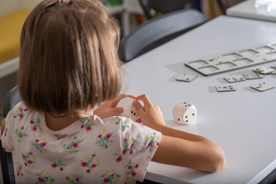 Little child learning numbers in Braille on dice 